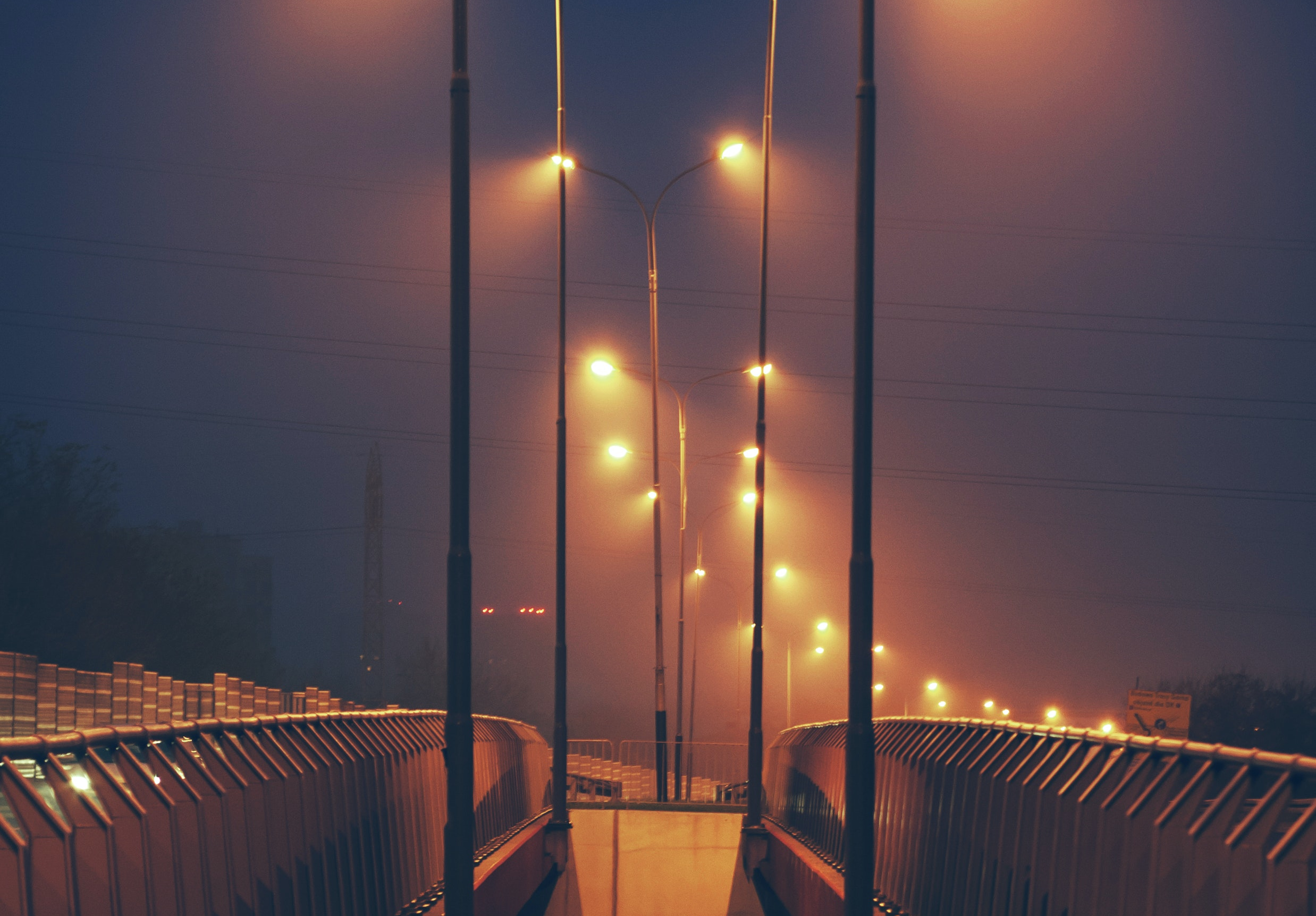 Street lights glowing at night along a walkway and road