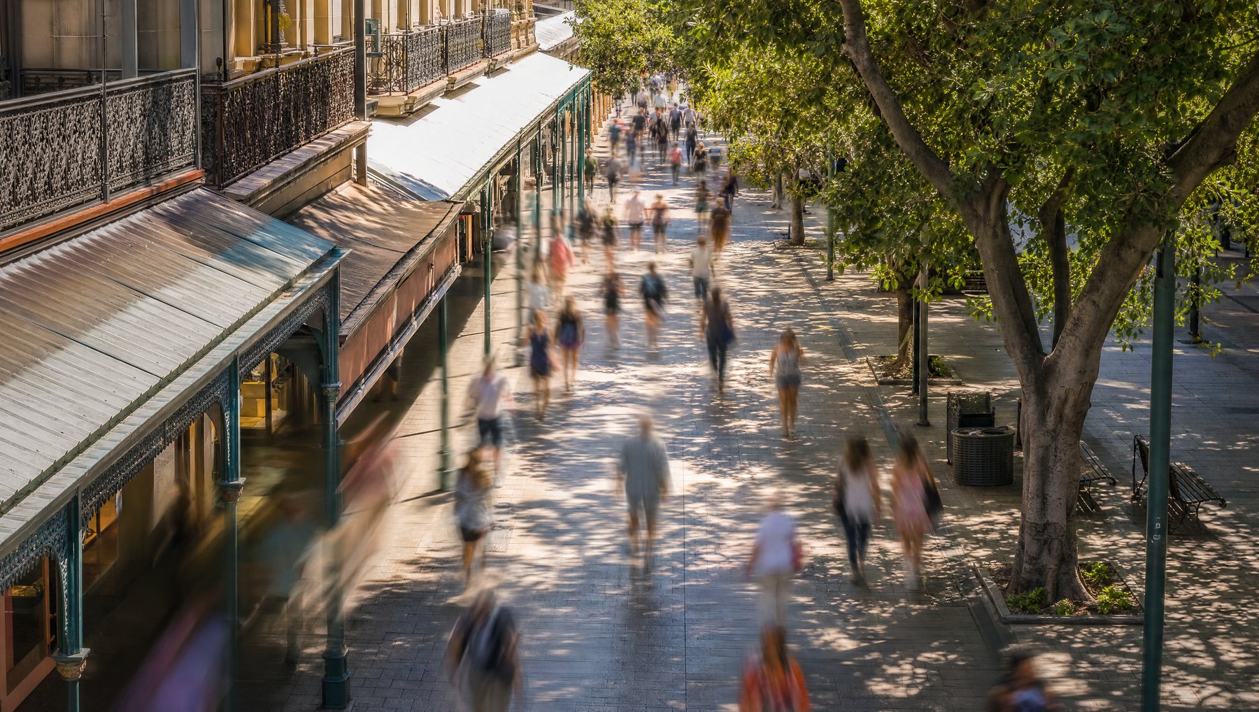 Elevated view of a busy pedestrian street with people rendered as anonymous motion blur