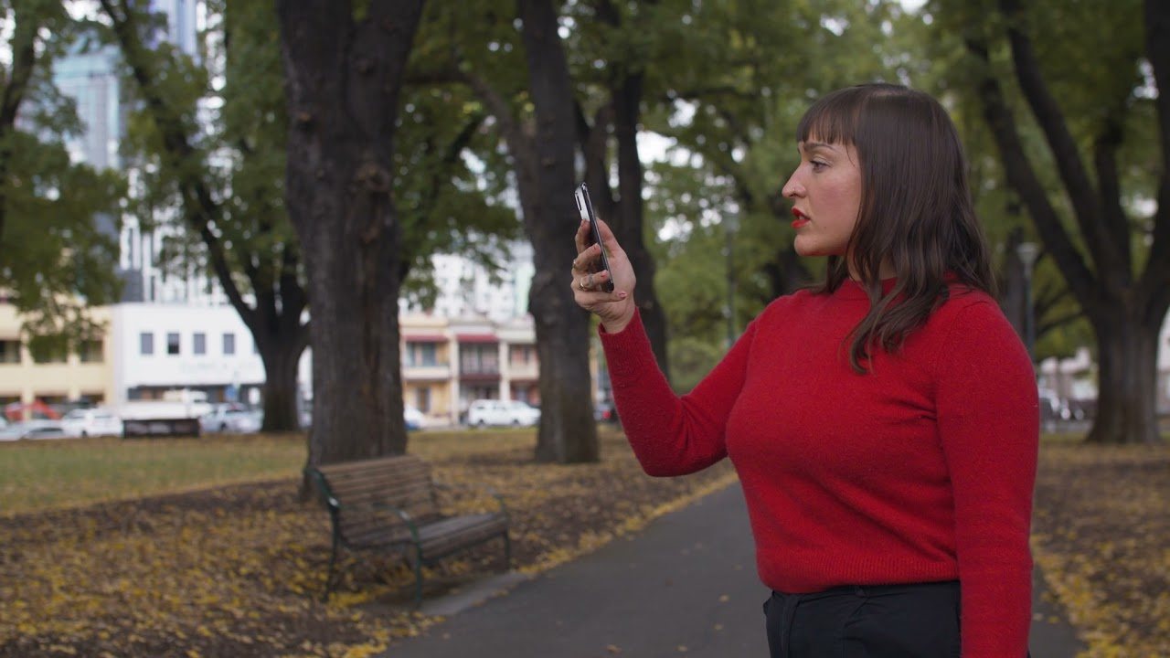 A visitor in a Melbourne park viewing live park data on a phone through the Phoria augmented reality app