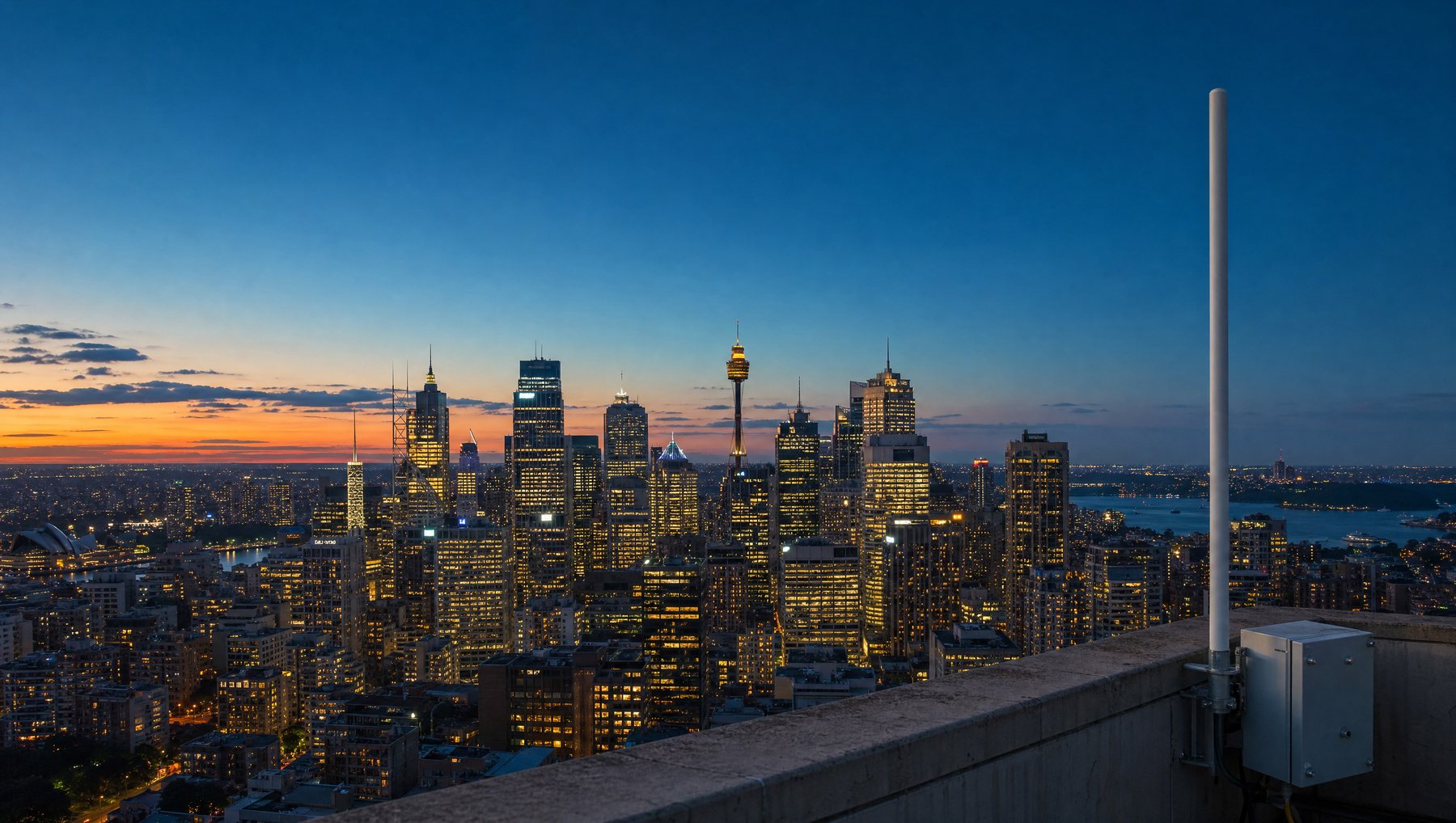 A rooftop antenna and weatherproof enclosure overlooking the Sydney skyline at dusk
