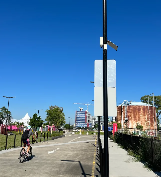 An nCounter people counting sensor mounted on a light pole beside a shared path in an urban riverside precinct