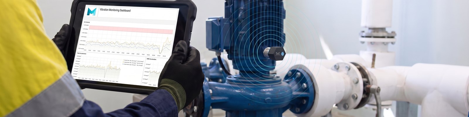 A maintenance technician reads a live vibration chart on a rugged tablet beside a water pump, with a small Meshed wireless vibration sensor fitted to the pump's motor